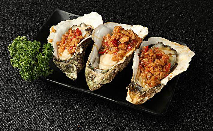 把海蛎子放在炉架上烤至稍微张口后,把做好的蒜蓉酱插入海蛎子里,继续