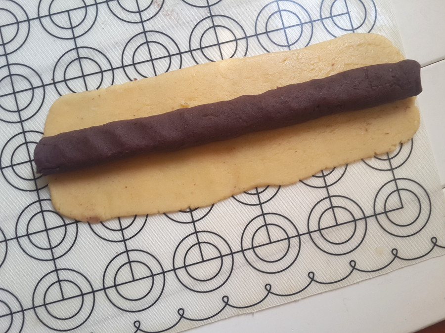 5.分成两份,擀成长方形,75克豆沙条搓成条放上.