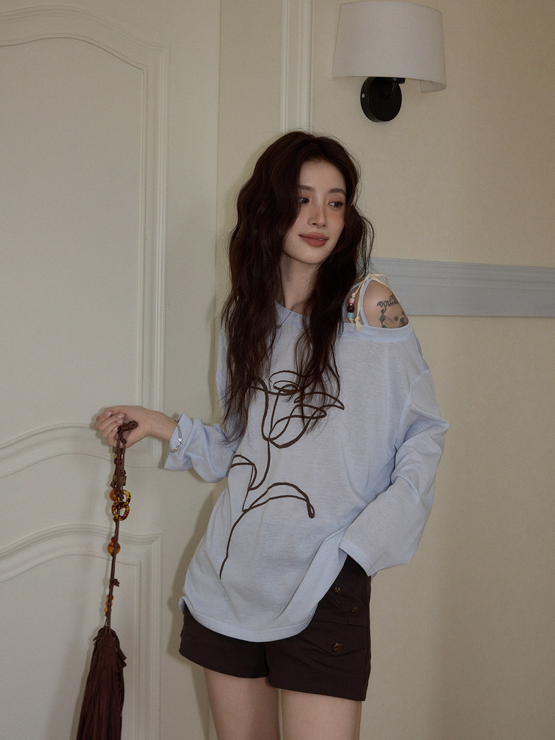 Model wearing a light blue oversized graphic long-sleeve top with dark shorts