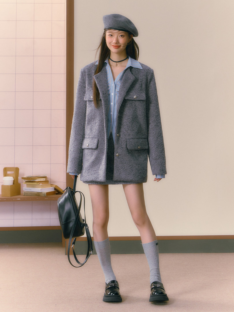 Model wearing a gray oversized blazer set with beret, black backpack, and loafers