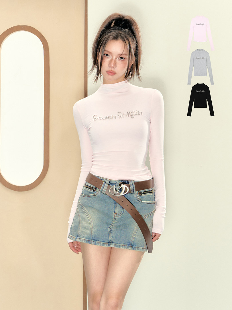 Model wearing a light pink fitted long-sleeve top with a denim mini skirt and belt