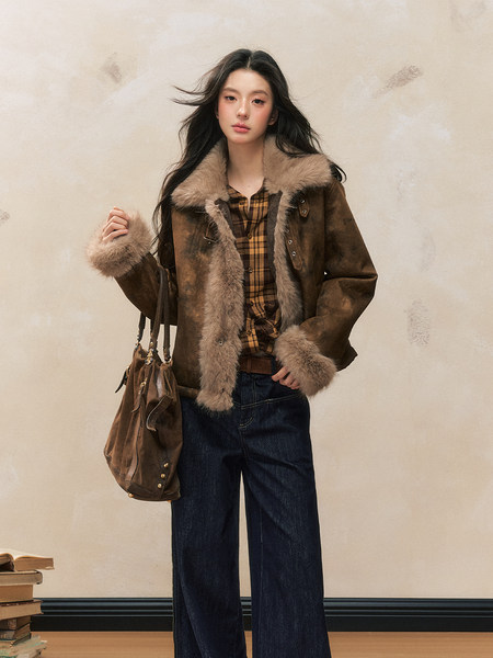 Model wearing a brown fur-trimmed jacket with plaid shirt, jeans, and a brown handbag