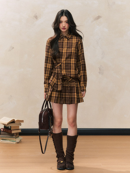 Model wearing a brown plaid shirt and pleated skirt set with knee-high socks and a backpack