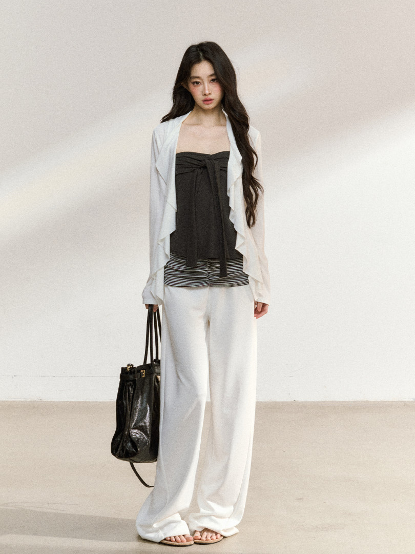 Model wearing a layered black-and-white fashion outfit with wide-leg white trousers