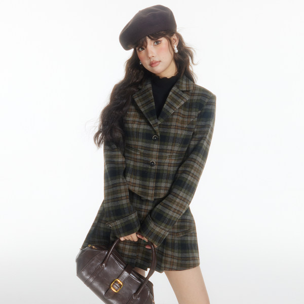 Model wearing a plaid blazer and matching skirt set with a beret and handbag