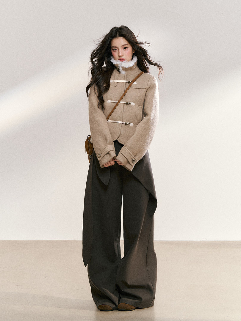 Model wearing a beige toggle-front jacket with wide dark trousers
