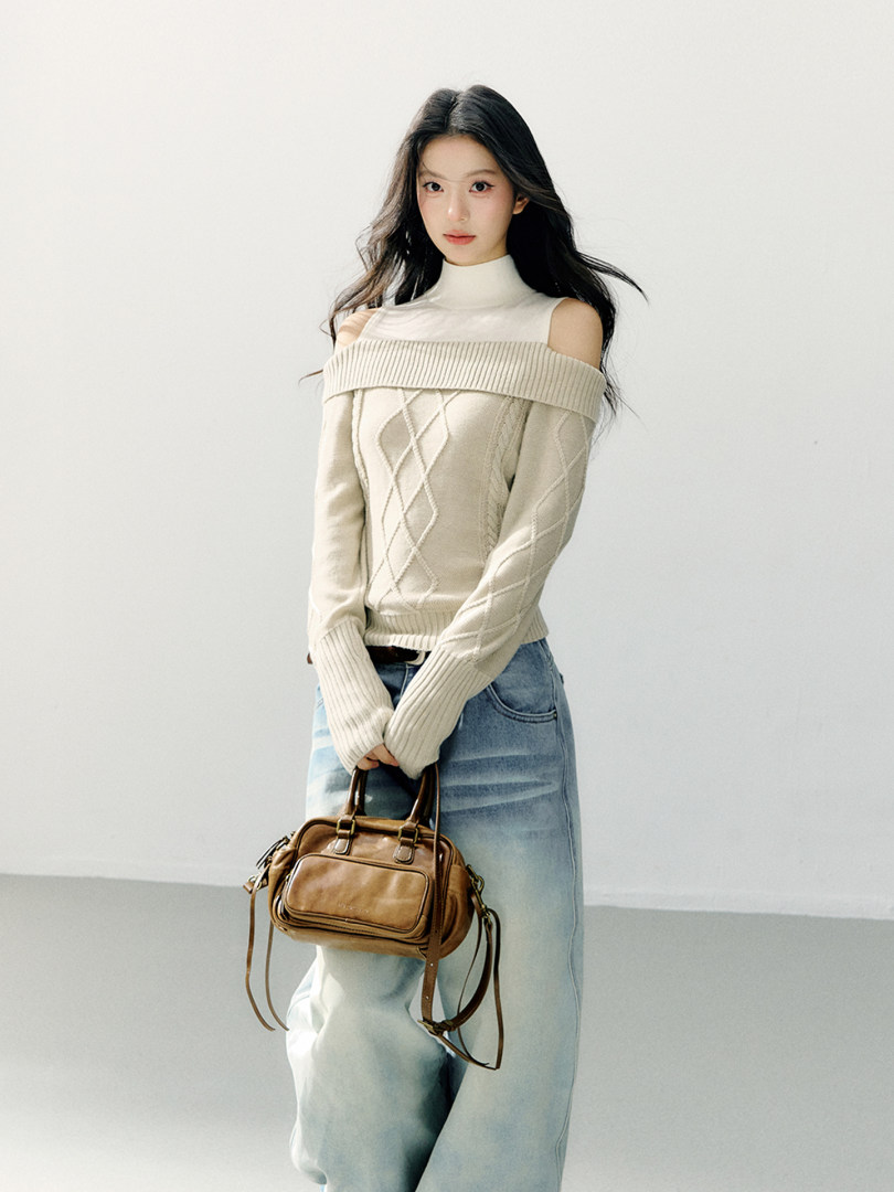Model wearing a cream off-shoulder knit sweater with a brown handbag