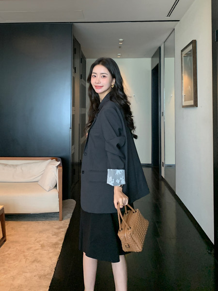 Woman wearing a black blazer outfit and holding a woven tote bag