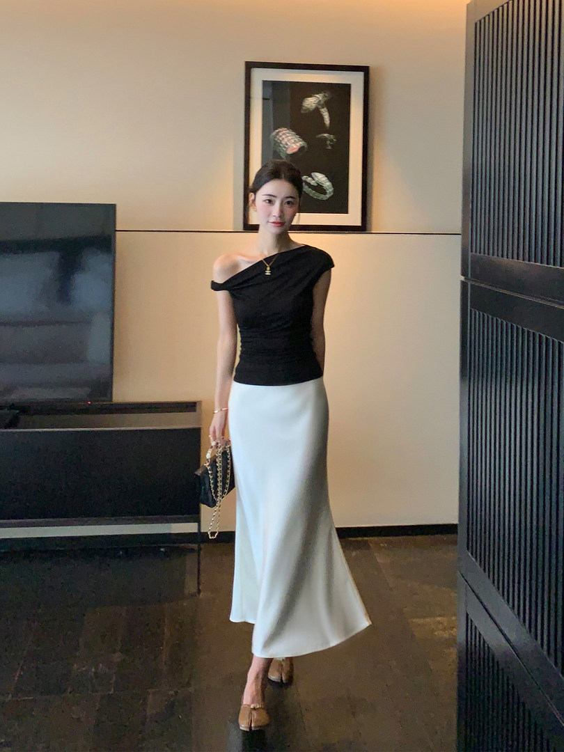 Woman wearing a black off-shoulder top with a white fitted maxi skirt
