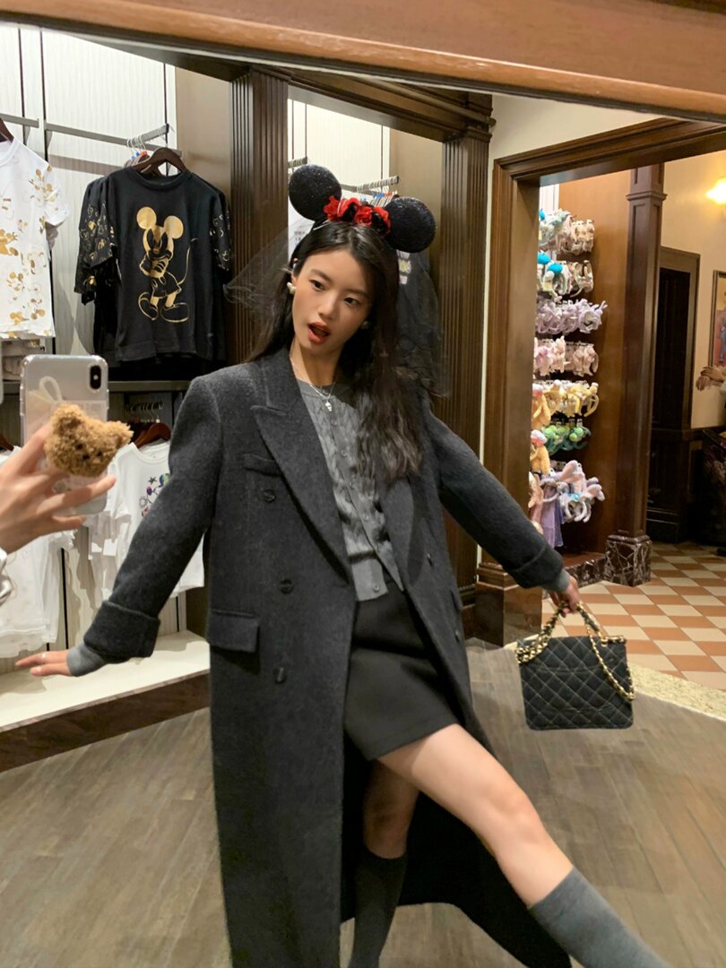 Woman wearing a dark gray long coat outfit in a store mirror selfie
