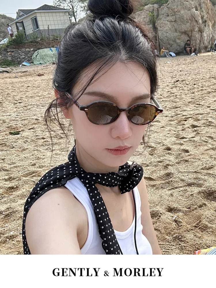 Brown oval sunglasses worn by a woman at the beach