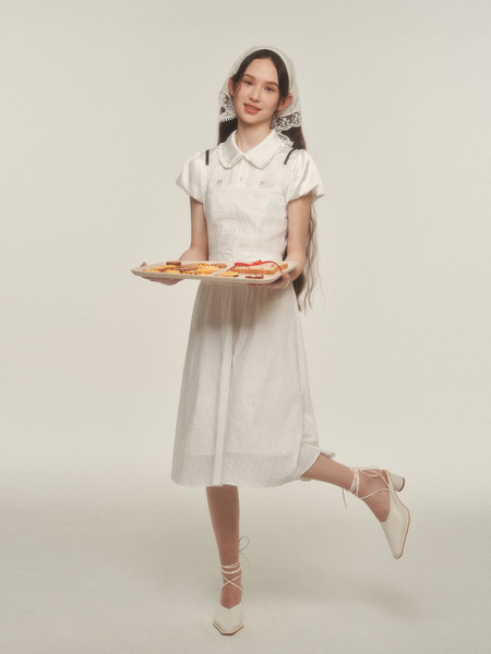 Woman wearing a white short-sleeve dress with lace head covering and white lace-up heels