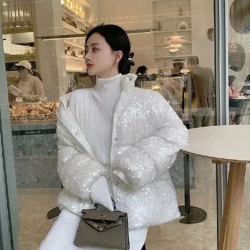 Ссылаясь на белую утку вниз по короткой куртке, женщины сгущаются.