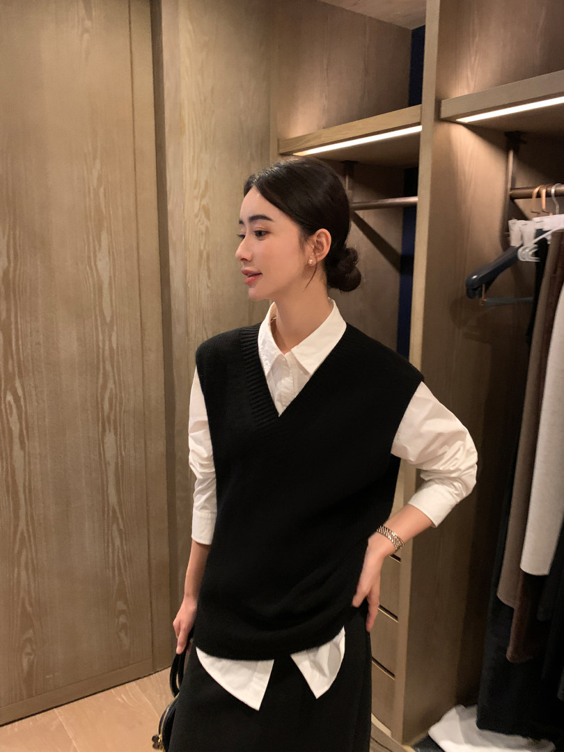 Woman wearing a black sweater vest over a white button-up shirt