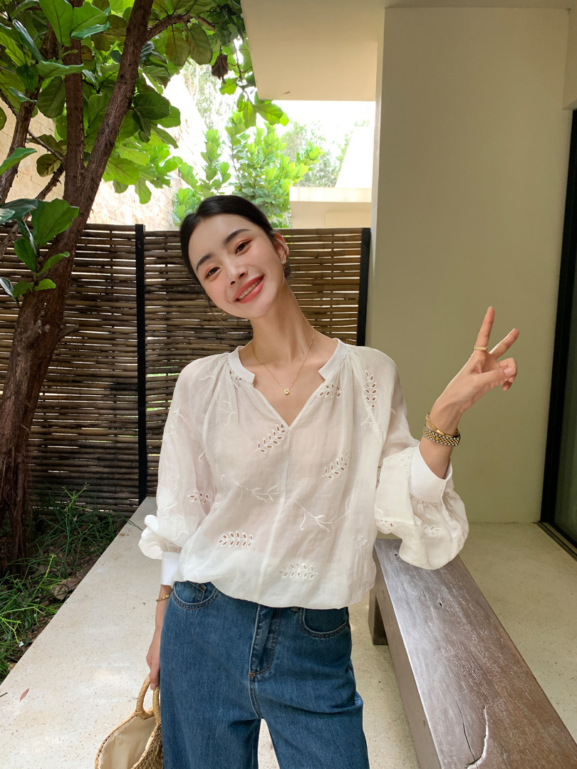 White embroidered sheer blouse worn by a model with blue jeans