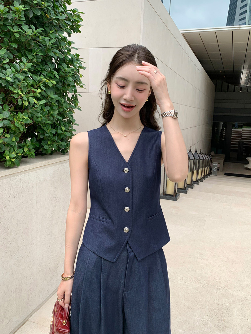 Woman wearing a navy sleeveless button-front vest and matching wide-leg pants
