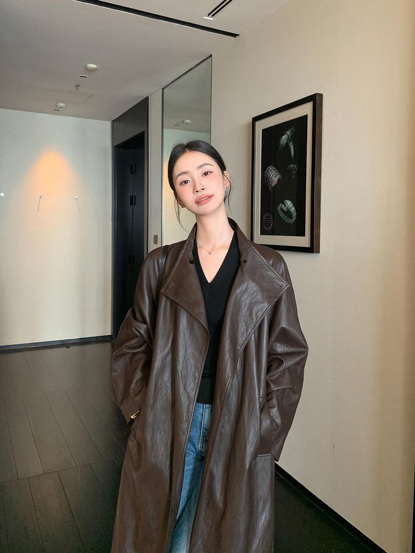 Model wearing a long brown leather coat over a black top and jeans
