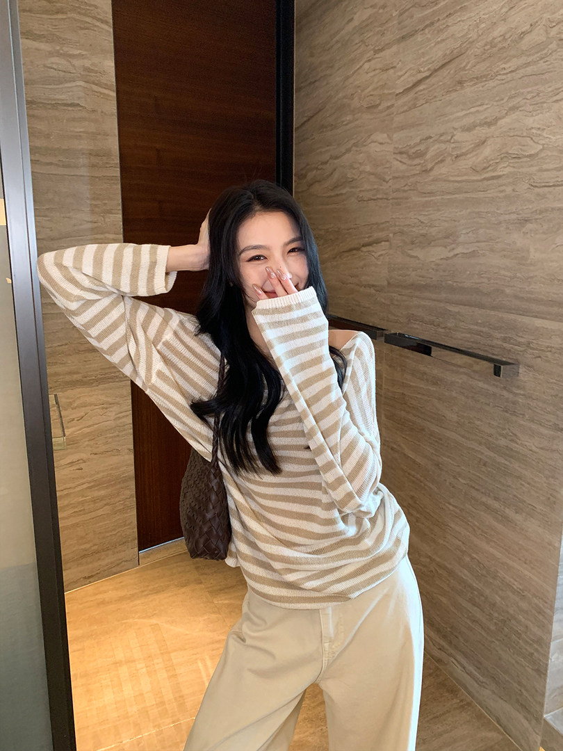 Woman wearing a beige and white striped oversized sweater and cream pants