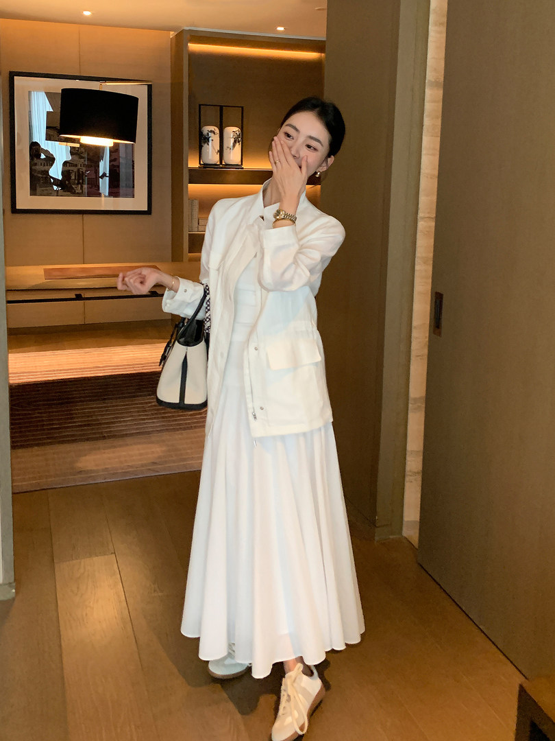Woman wearing a white long dress with a white jacket and handbag