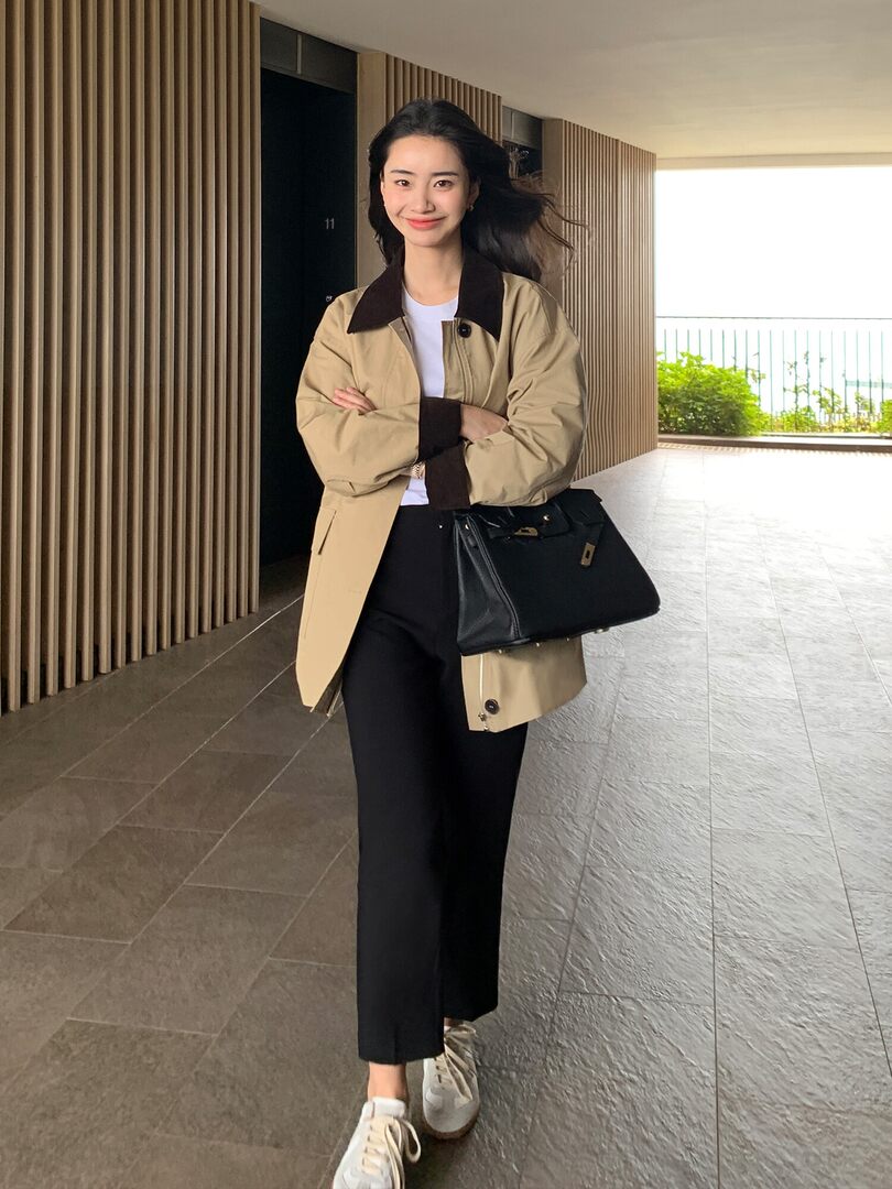 Model wearing a beige-and-black casual outfit with a black handbag