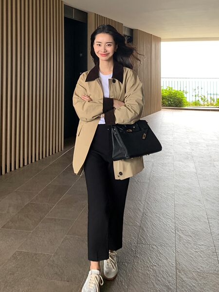 Model wearing a beige-and-black casual outfit with a black handbag