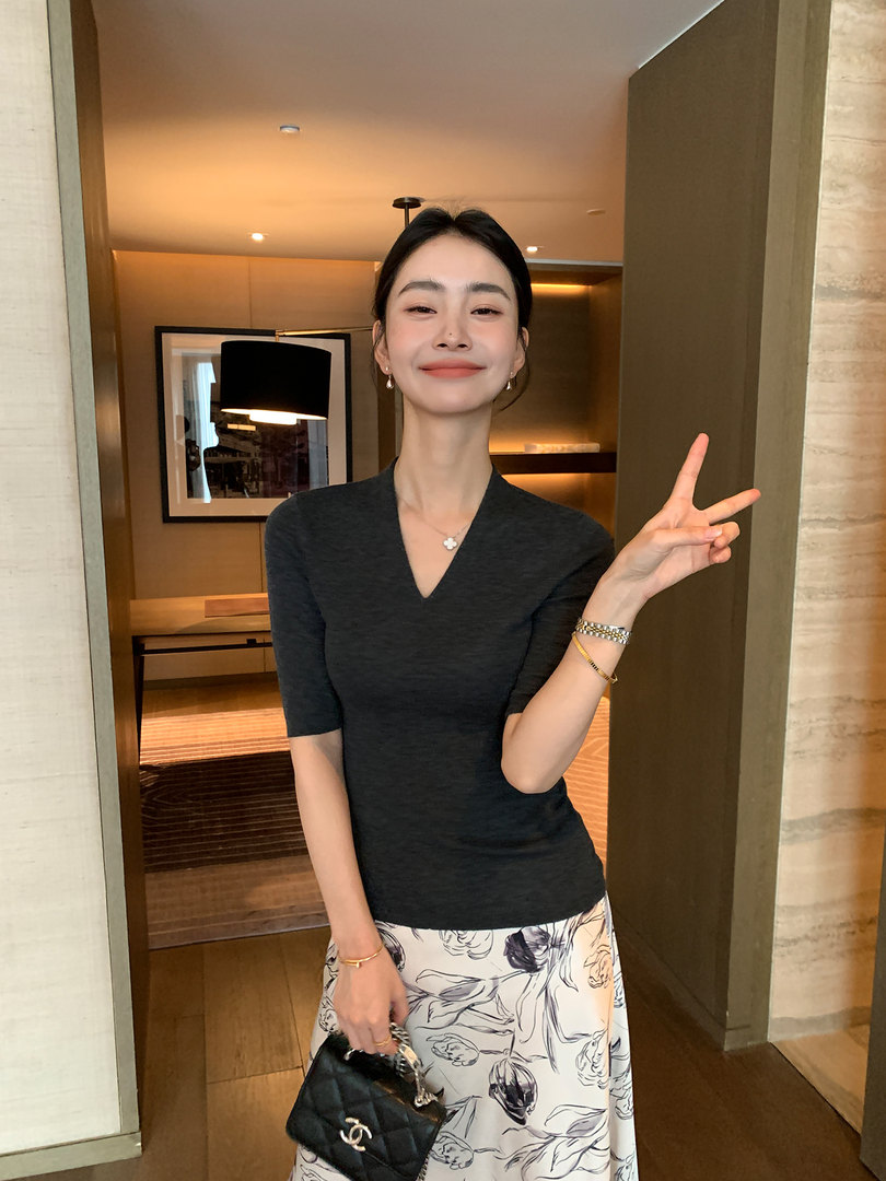 Woman wearing a black fitted top with a floral skirt and a black quilted handbag