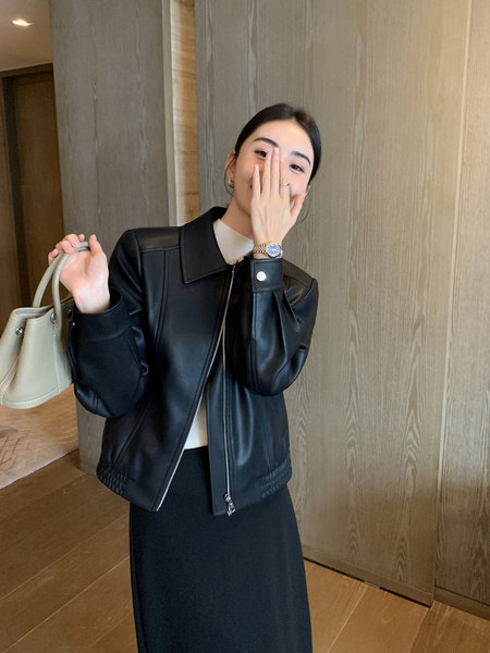 Black leather jacket worn by a woman with a beige handbag