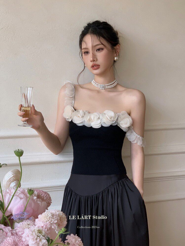Black off-shoulder dress with white floral trim worn by a model