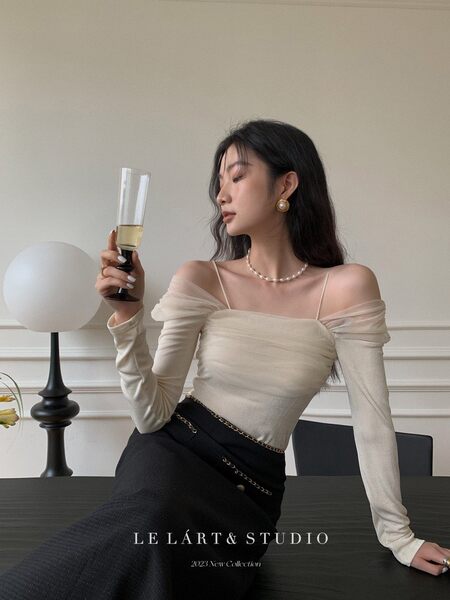 Woman wearing a cream off-shoulder fitted top with a black skirt