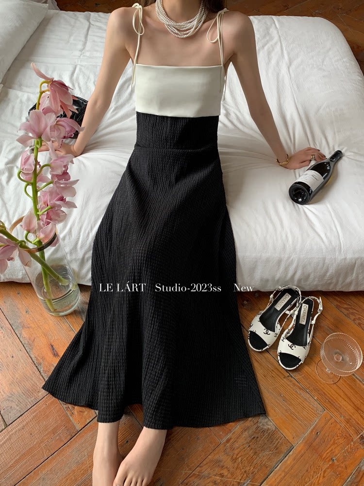 Model wearing a black and white spaghetti-strap maxi dress with pearl necklace