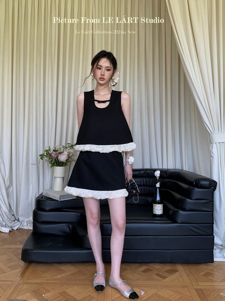 Black sleeveless mini dress with white ruffle trim worn by a model