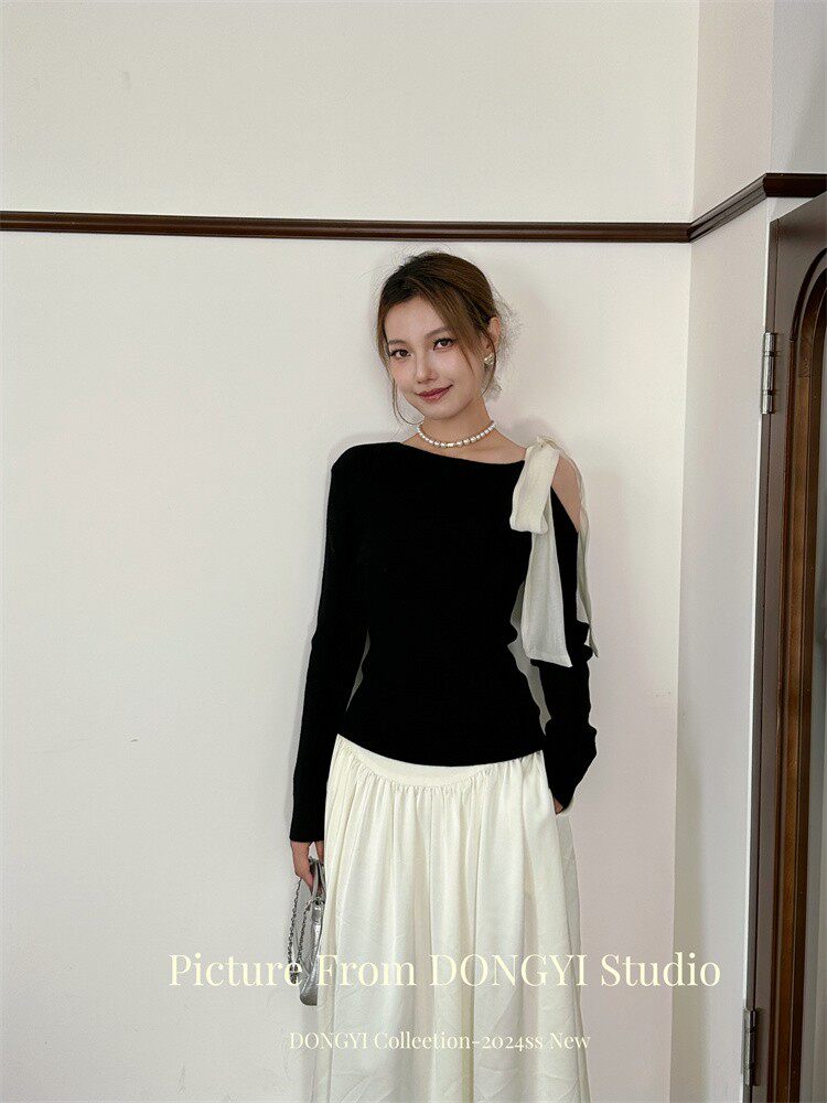 Model wearing a black one-shoulder top with a white long skirt