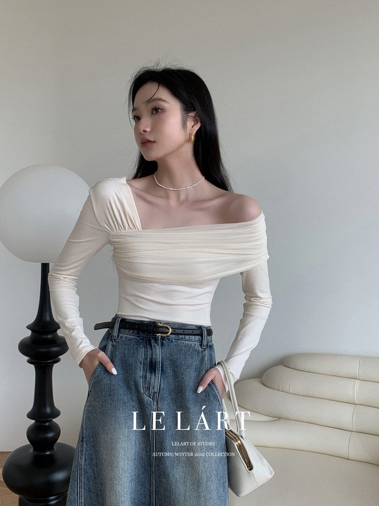 Woman wearing a cream off-shoulder long-sleeve top with blue jeans
