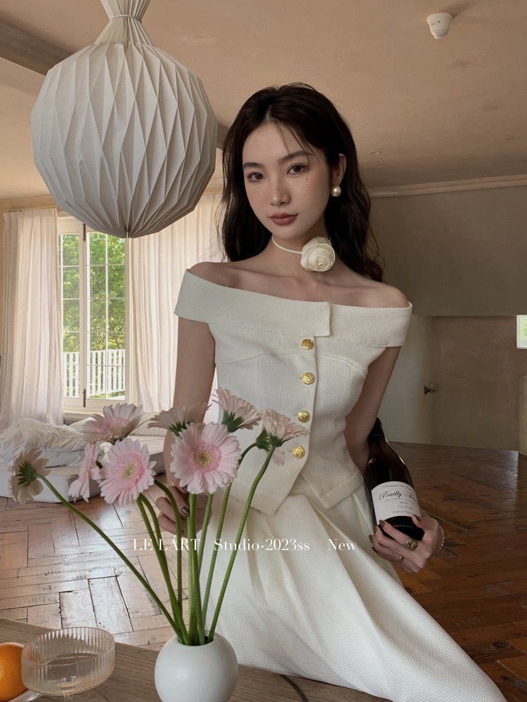 Woman wearing an off-shoulder white dress with gold buttons