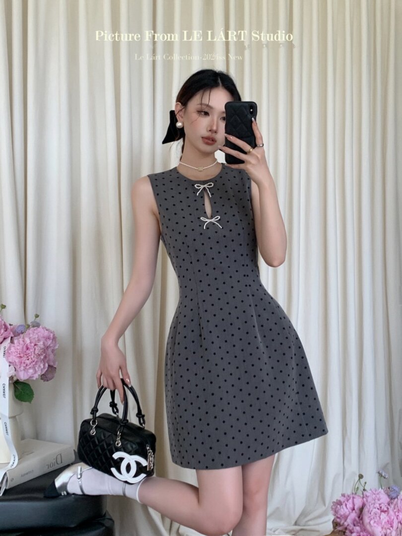 Woman wearing a gray polka dot sleeveless dress with bow details