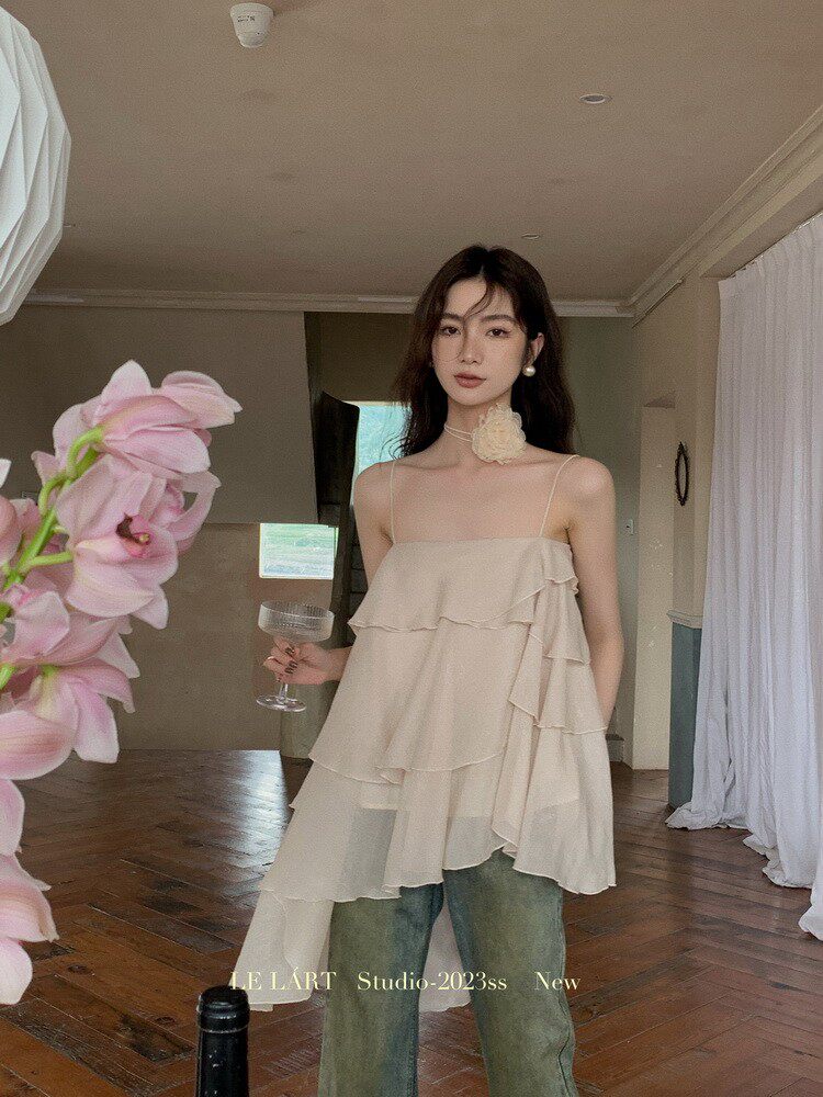 Woman wearing a beige ruffled sleeveless top with jeans