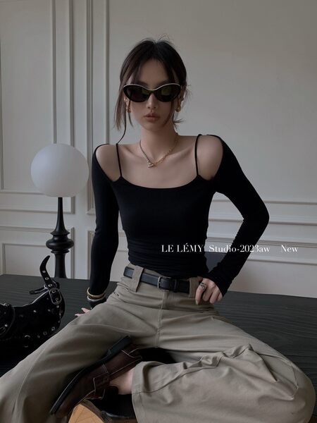 Model wearing a black long-sleeve fitted top with beige wide-leg pants and sunglasses