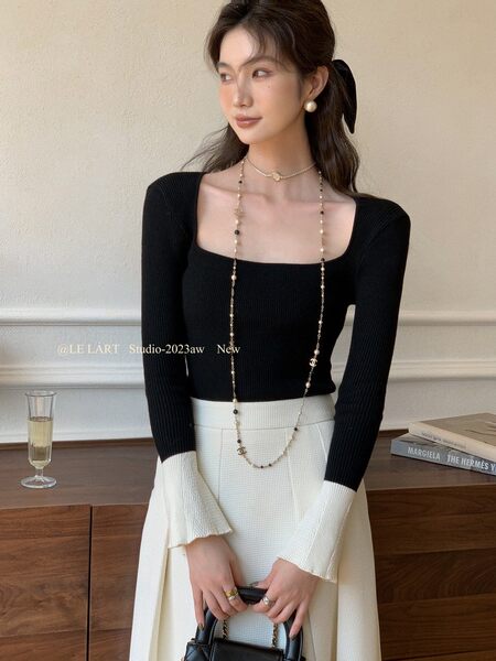 Woman wearing a black long-sleeve square-neck knit top with a white skirt