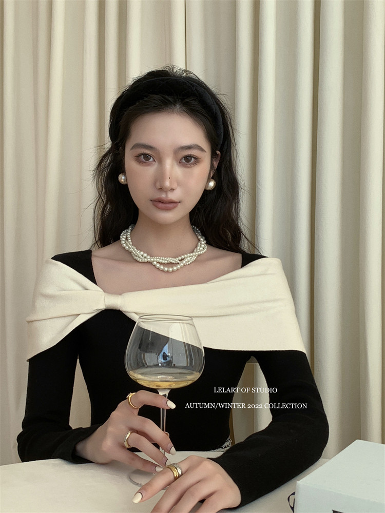 Black off-shoulder dress worn by a model with pearl jewelry