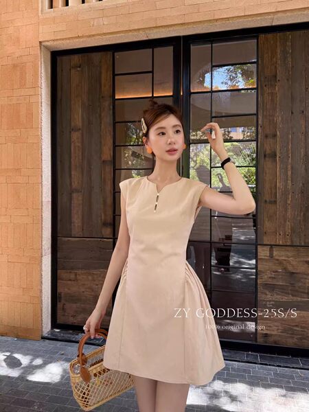 Model wearing a beige sleeveless mini dress with a flared skirt and woven handbag