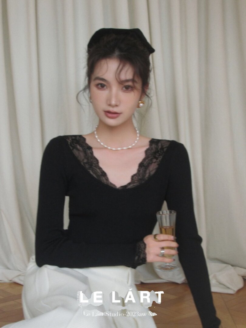 Black long-sleeve lace-trim top worn by a model with white pants