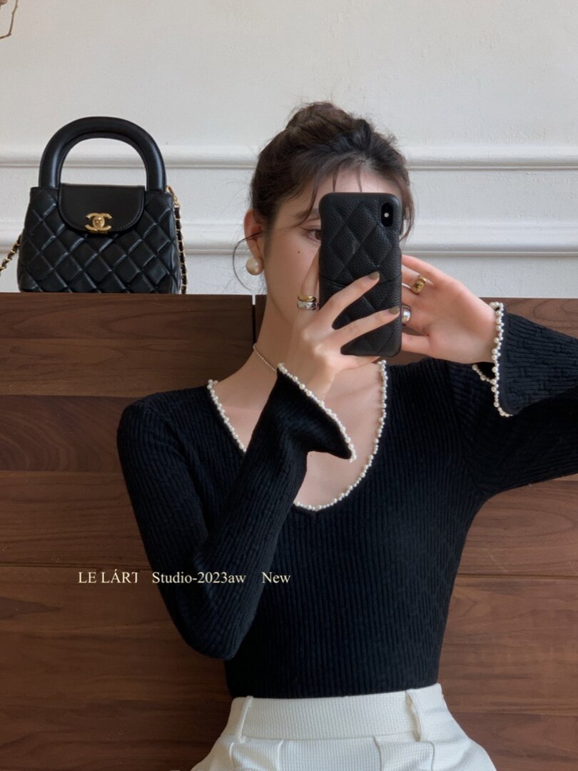 Black ribbed long-sleeve top with pearl trim worn by a model