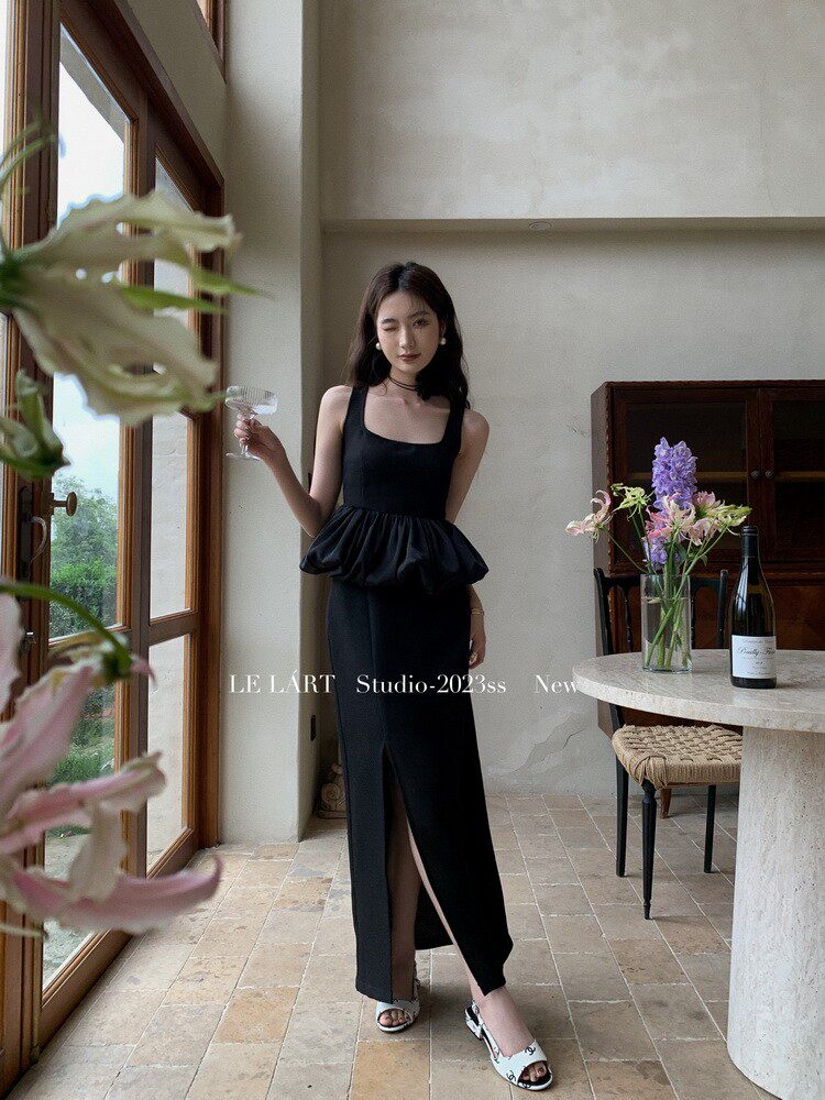 Black sleeveless maxi dress with a peplum waist and front slit worn by a model