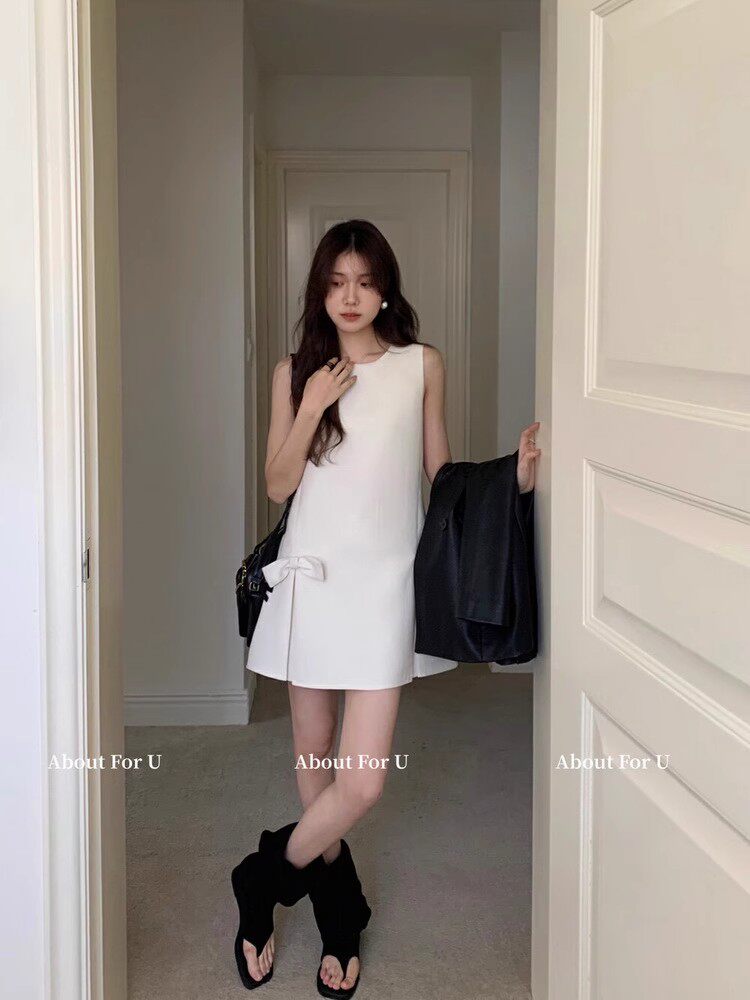 White sleeveless mini dress worn with black boots in a mirror photo