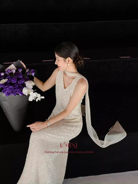 Woman wearing a sparkling ivory evening gown with a long sheer scarf