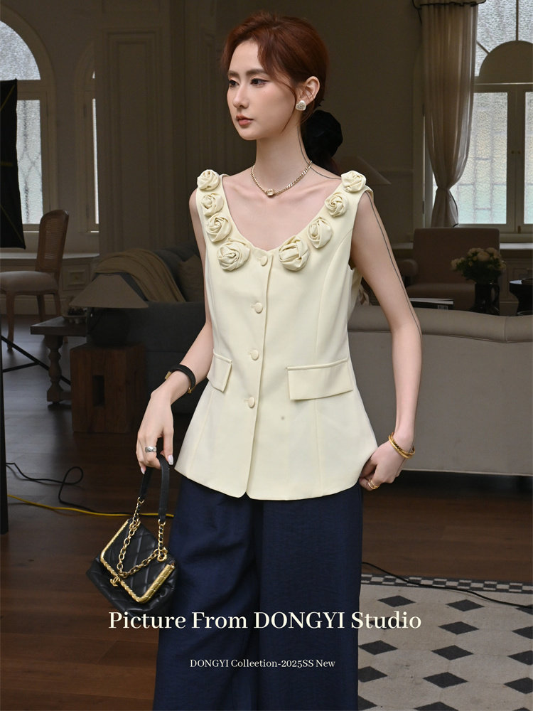 Model wearing a cream sleeveless embellished top with navy wide-leg pants