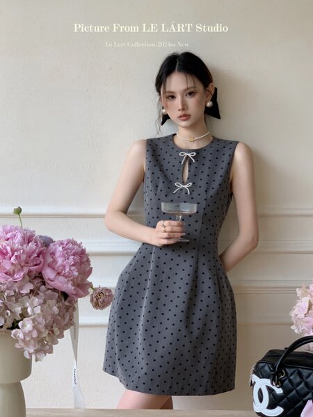 Model wearing a gray polka dot sleeveless mini dress with bow details