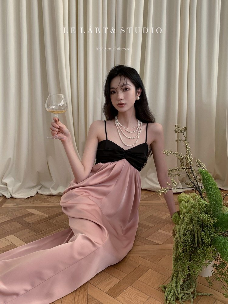 Model wearing a black-and-pink draped evening dress with pearl necklace
