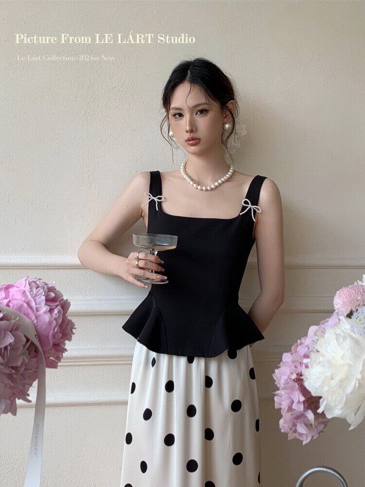Woman wearing a black peplum camisole top with a white polka dot skirt
