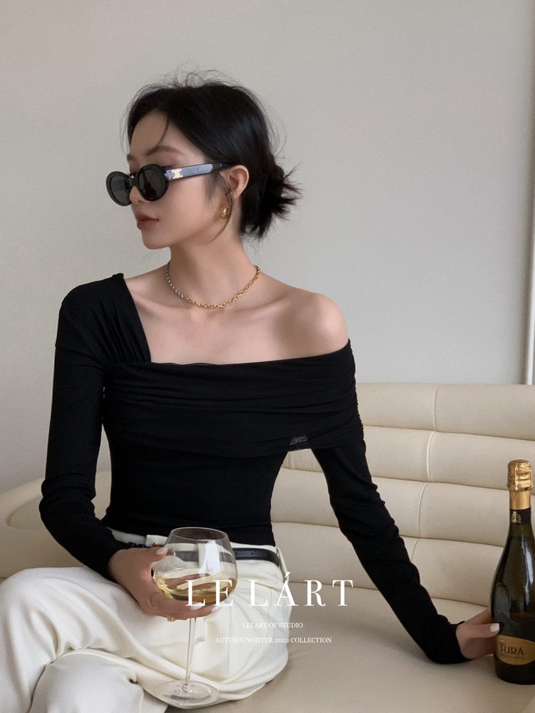Model wearing a black off-shoulder long-sleeve top with white pants